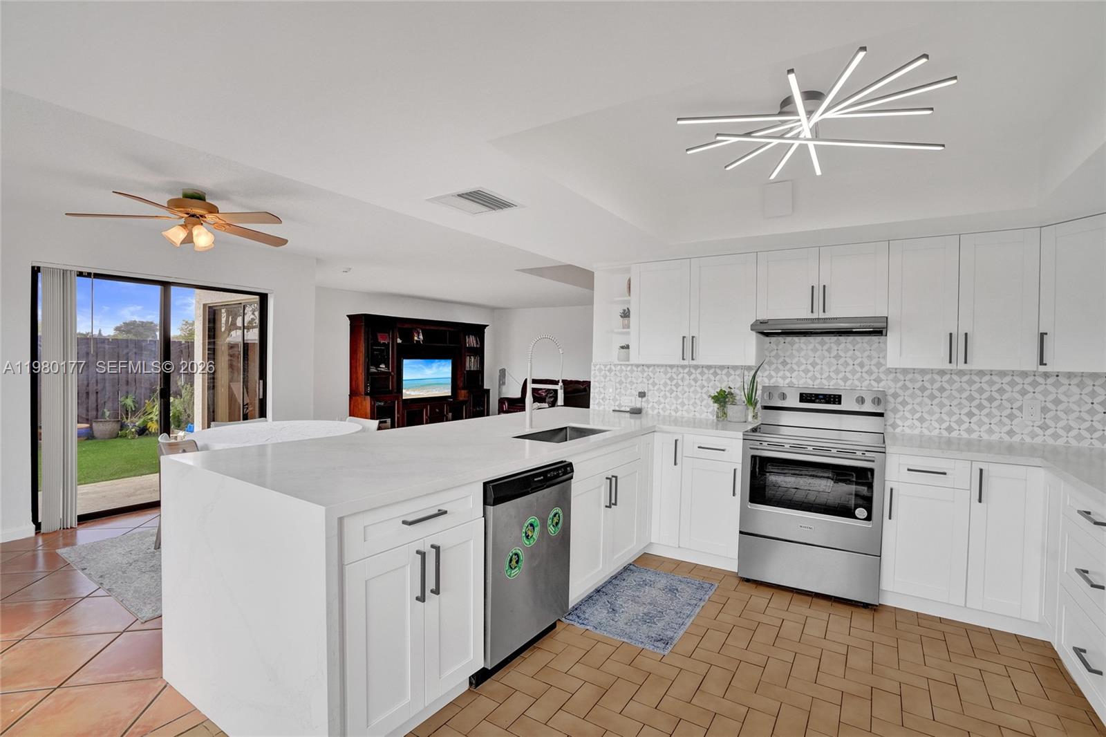 A kitchen with white cabinets, a quartz island, stainless steel appliances, and tiled flooring — 15292 SW 46th Ln Br # 64, Miami FL 33185, MIAMI, FL