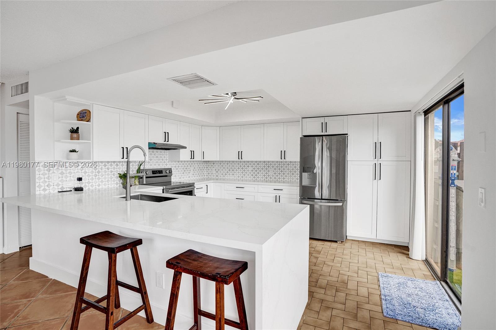 A modern kitchen features white cabinetry, quartz countertops, stainless steel appliances, and a breakfast bar — 15292 SW 46th Ln Br # 64, Miami FL 33185, MIAMI, FL