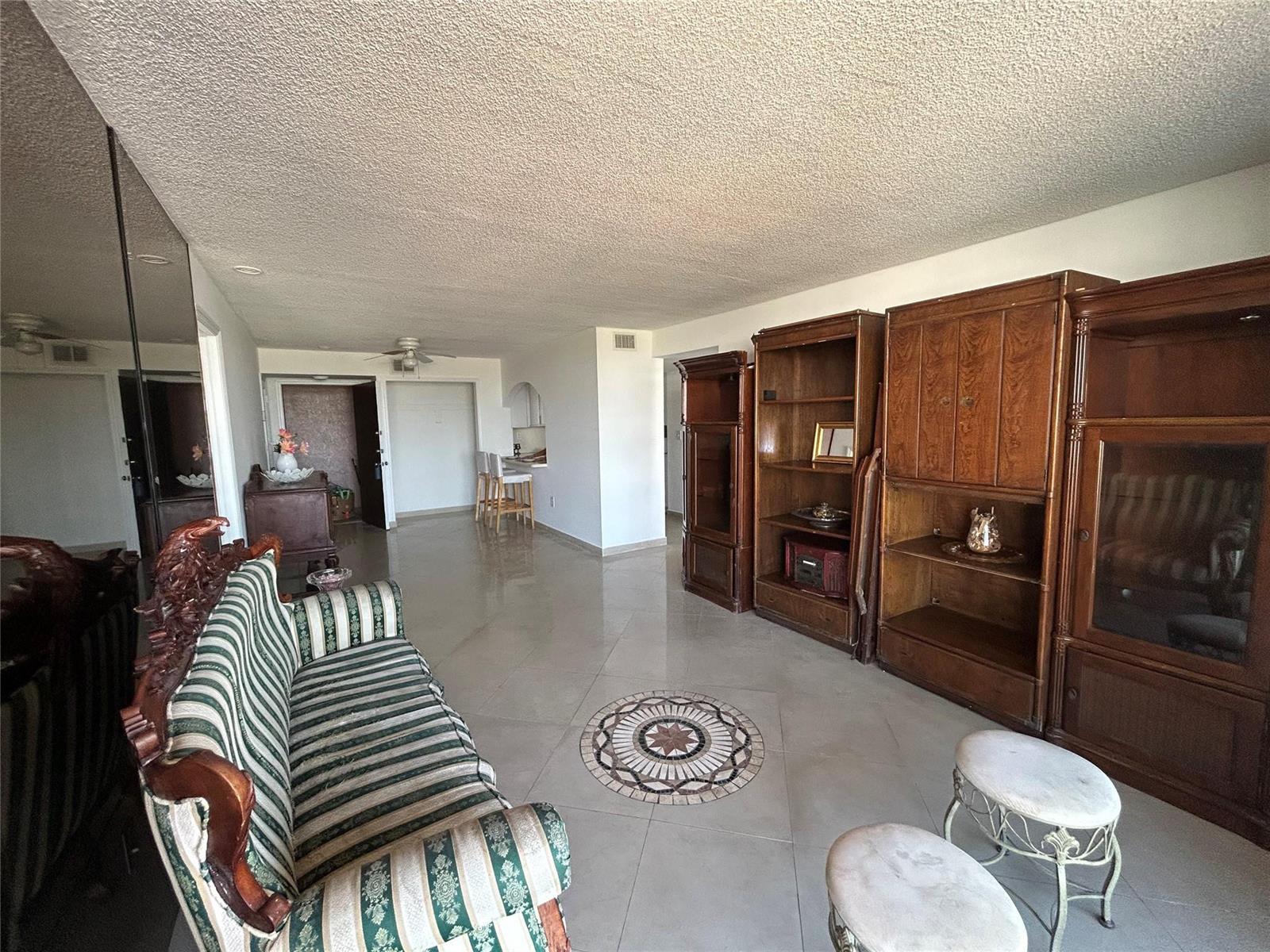 A living room features tiled floors, a striped sofa, and large wooden wall cabinets — 7040 Coral Way # 501, Miami FL 33155, MIAMI, FL