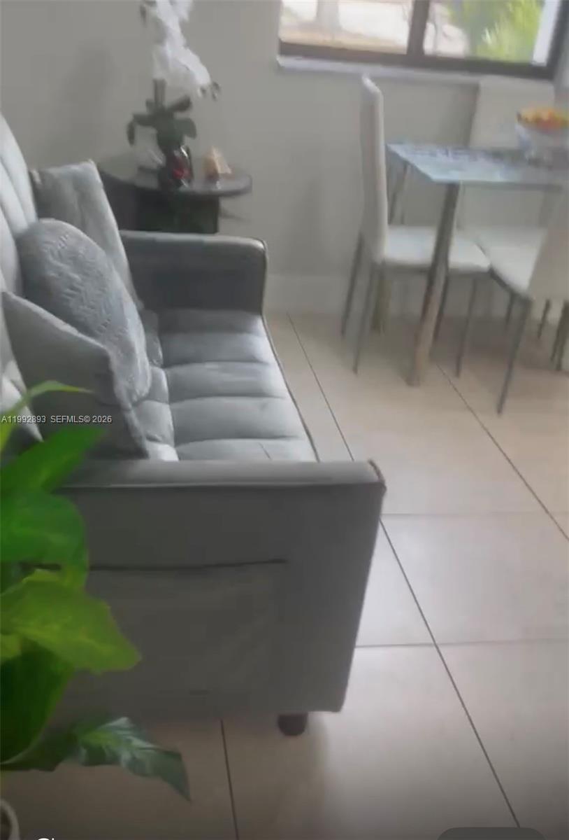 A gray sofa sits in a room with light-colored tile flooring and a dining set — 14554 SW 161 Ct, Miami FL 33196, MIAMI, FL