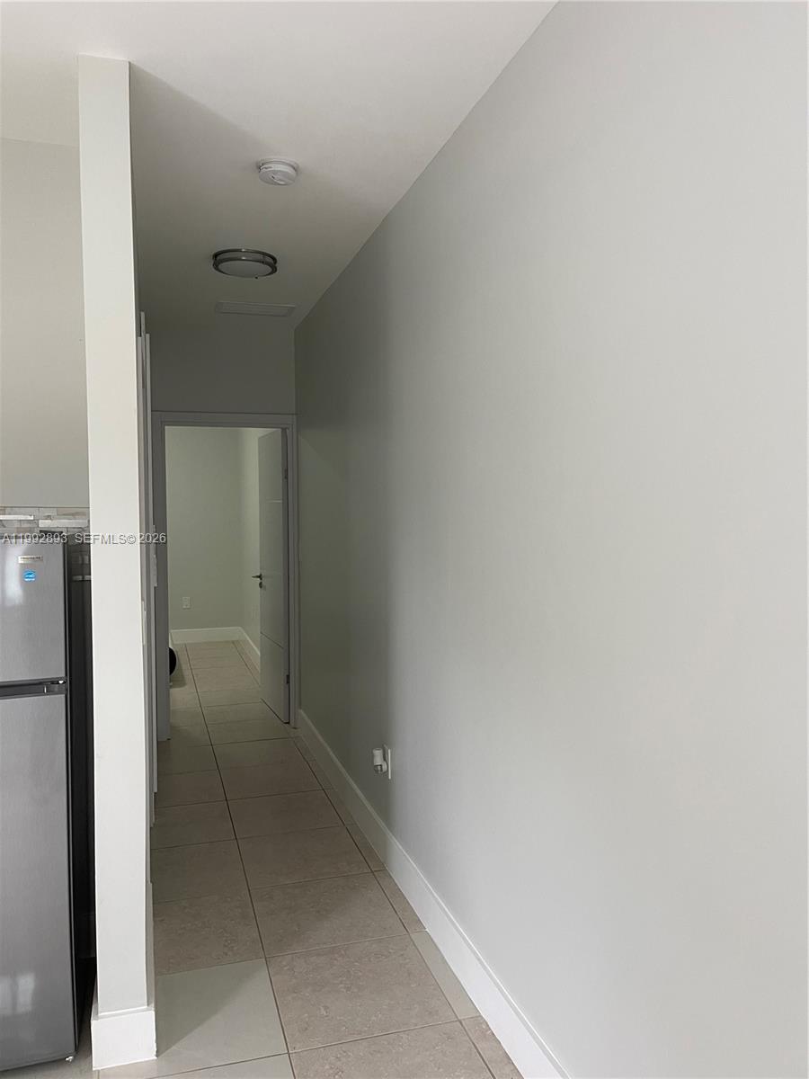 A hallway with light-colored walls and tile flooring leads to an open doorway — 14554 SW 161 Ct, Miami FL 33196, MIAMI, FL