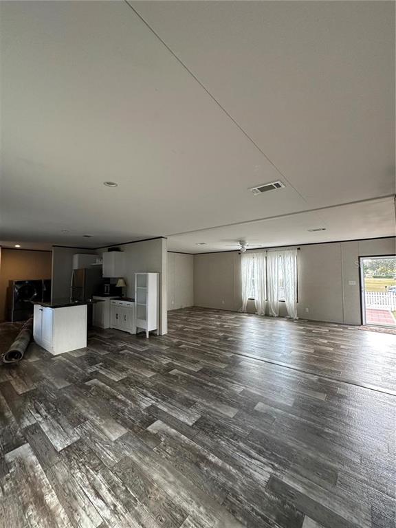 An open-concept living and kitchen area features wood-look flooring and a white kitchen island — 618 1 ST STREET, POLK CITY, FL