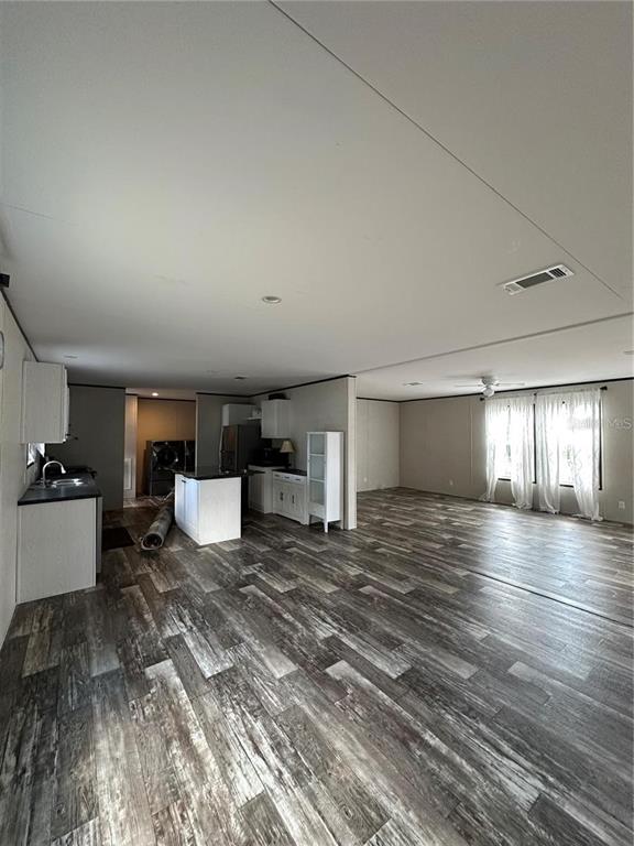 An open-concept room features wood-look flooring, a kitchen area, and a living space with curtains — 618 1 ST STREET, POLK CITY, FL