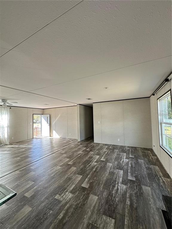 An open-concept living area features wood-look flooring, light-colored walls, and a view of an entryway — 618 1 ST STREET, POLK CITY, FL