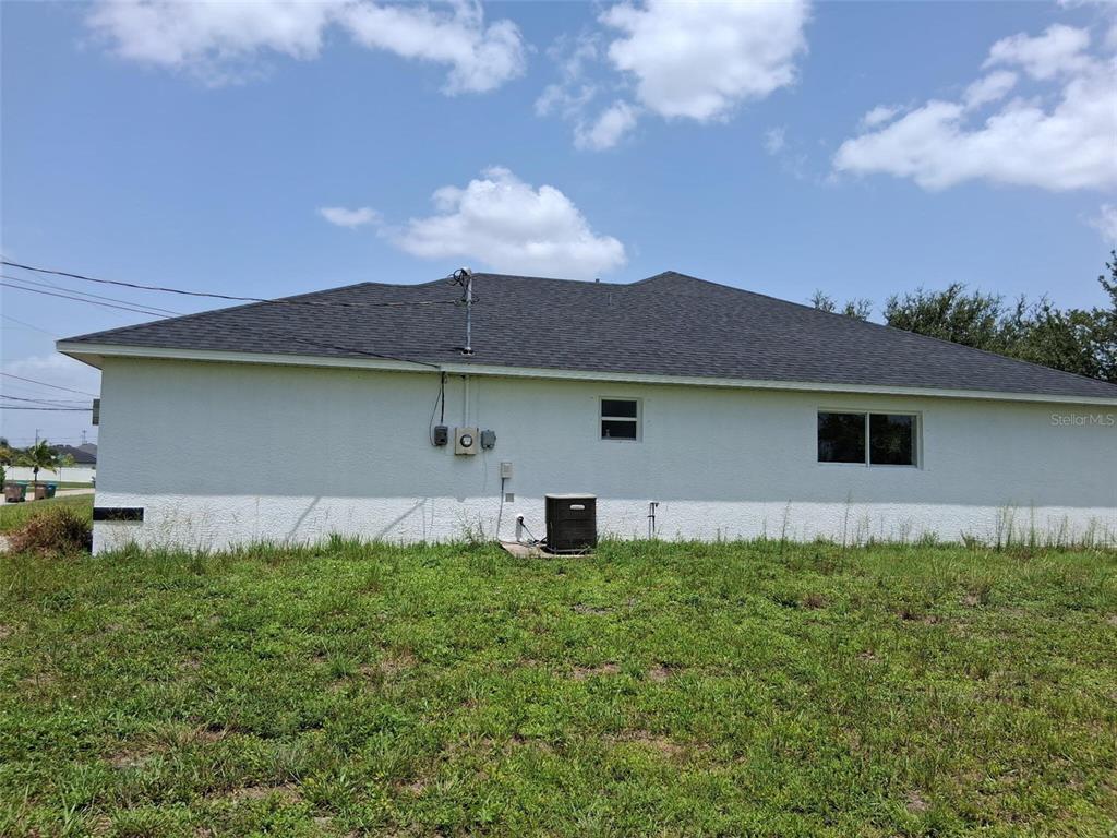 The exterior rear view of a single-story house features a white stucco wall and roof — 850 SW 15TH STREET, CAPE CORAL, FL