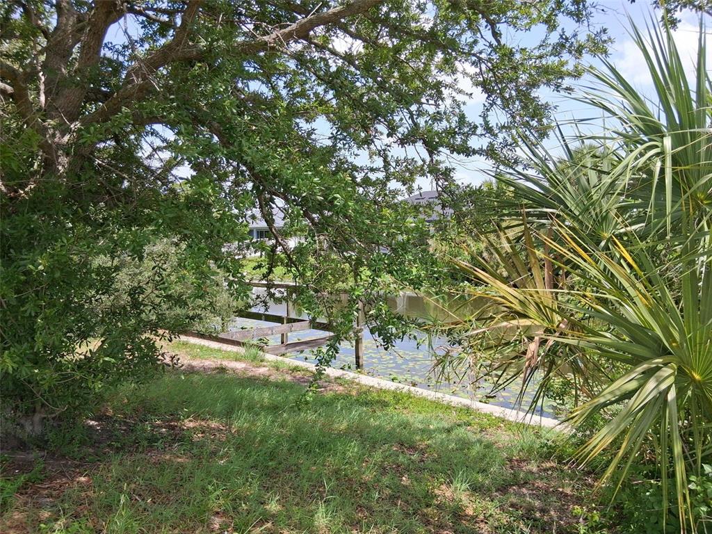 A view of a small canal with a wooden dock surrounded by trees and vegetation — 850 SW 15TH STREET, CAPE CORAL, FL
