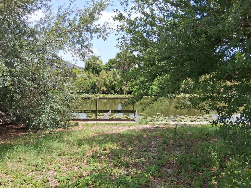 A wooden dock extends into a pond surrounded by trees and lily pads — 850 SW 15TH STREET, CAPE CORAL, FL