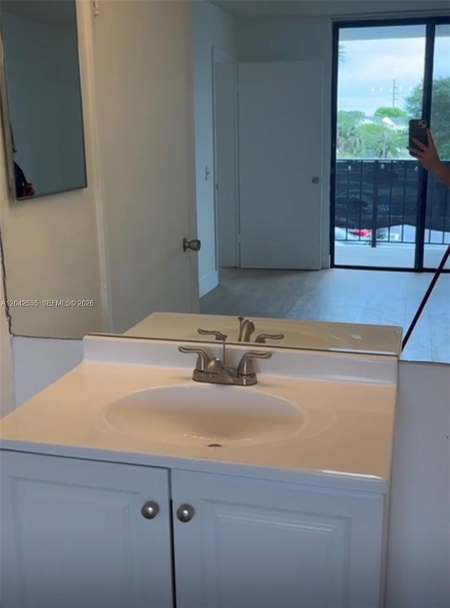 A bathroom vanity with a white cabinet and sink sits before a large wall mirror — 738 Executive Center Dr # 23, West Palm Beach FL 33401, WEST PALM BEACH, FL