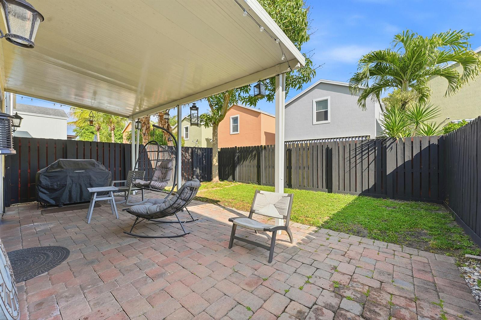 A paved patio with a covered seating area, outdoor furniture, and a fenced backyard — 3221 John's Place, Palm Springs FL 33461, PALM SPRINGS, FL