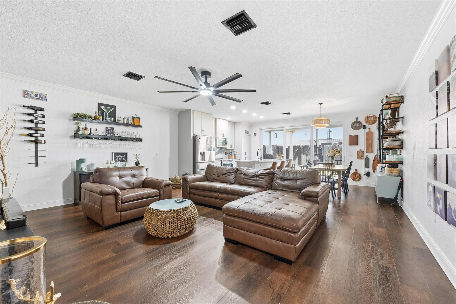 A living room with brown leather furniture, wood floors, and an open-concept kitchen — 3221 John's Place, Palm Springs FL 33461, PALM SPRINGS, FL