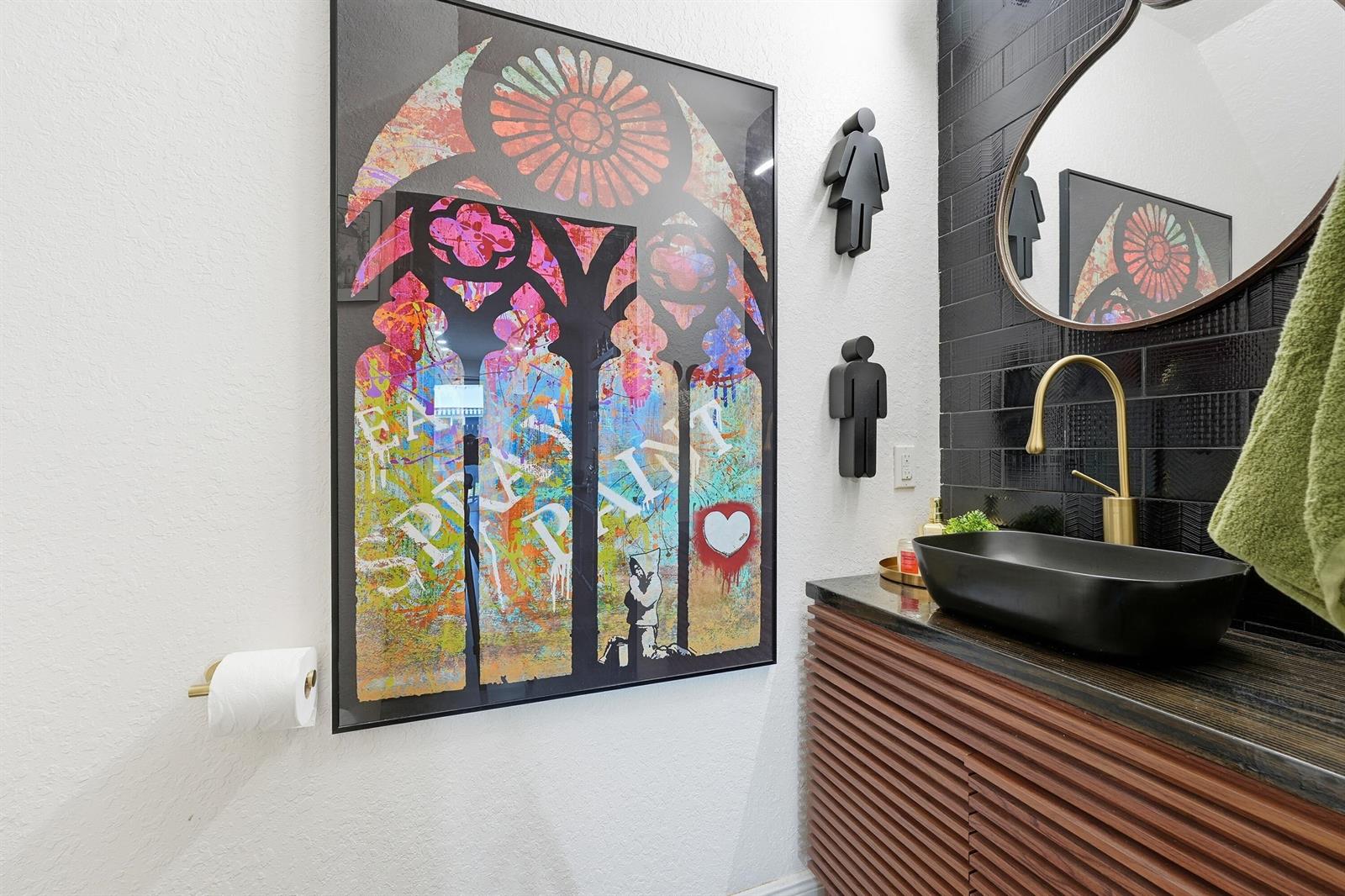 A modern powder room features a black vessel sink, gold faucet, and Banksy-style wall art — 3221 John's Place, Palm Springs FL 33461, PALM SPRINGS, FL