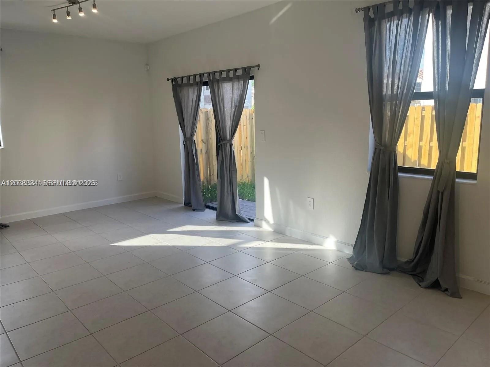 A paved street curves past a sidewalk with a yellow tactile pad and townhomes — 11935 SW 246th Ter, Miami FL 33032, MIAMI, FL