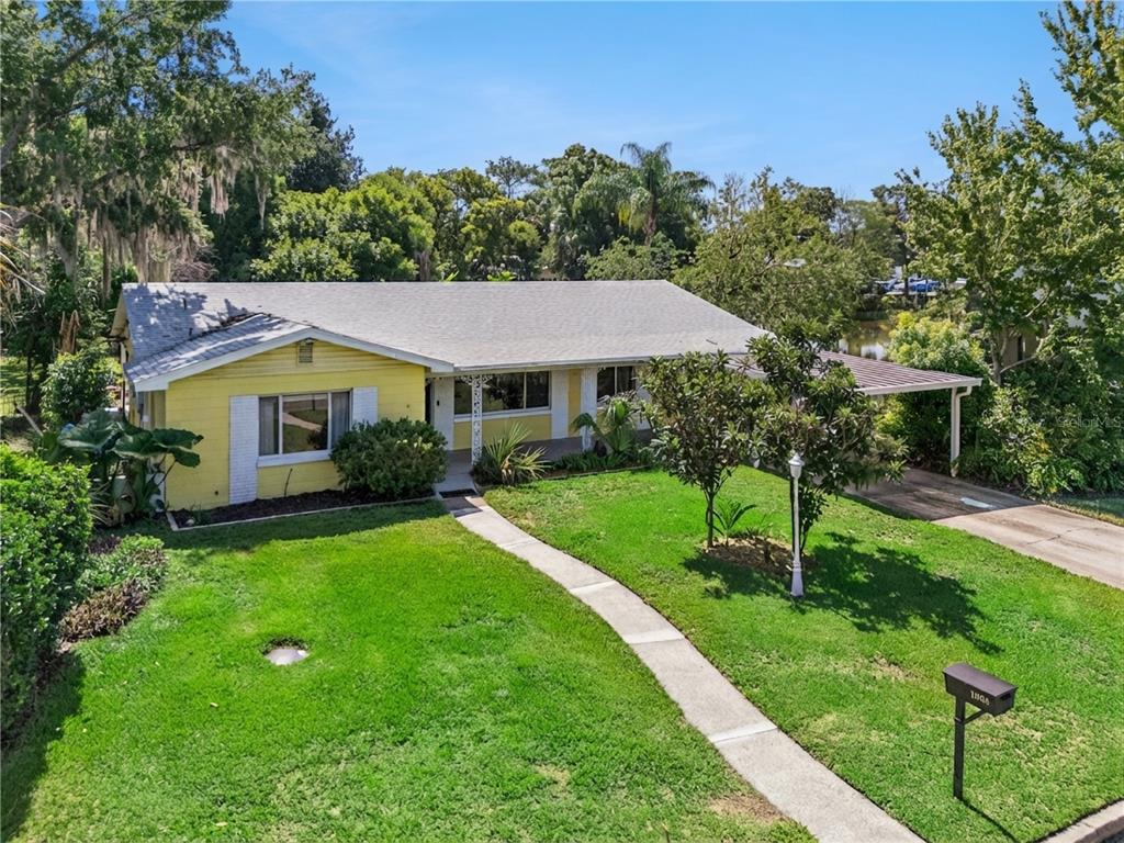 A yellow single-story house with a front lawn, a walkway, and a carport — 1003 LAKE BELL DRIVE, WINTER PARK, FL