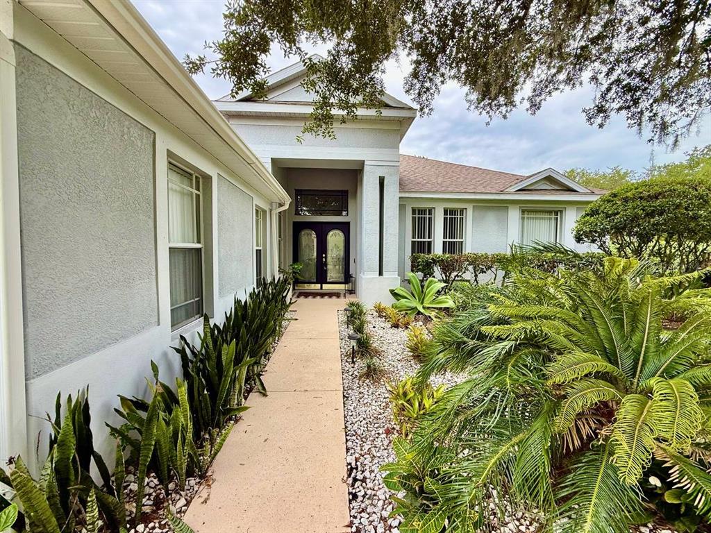 A concrete walkway leads to the front entrance of a house with light-colored exterior walls — 4301 RIVER CLOSE BOULEVARD, VALRICO, FL