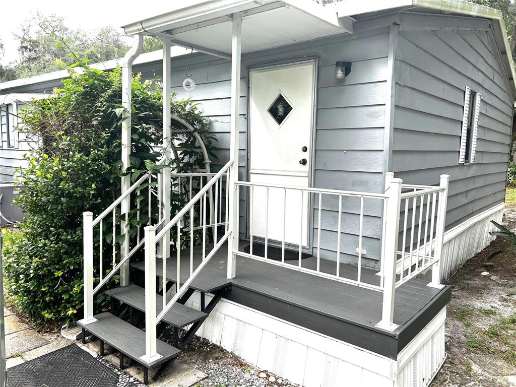A light gray mobile home features a small front porch with white railings and stairs — 3935 E LAKE PARK DRIVE, HERNANDO, FL
