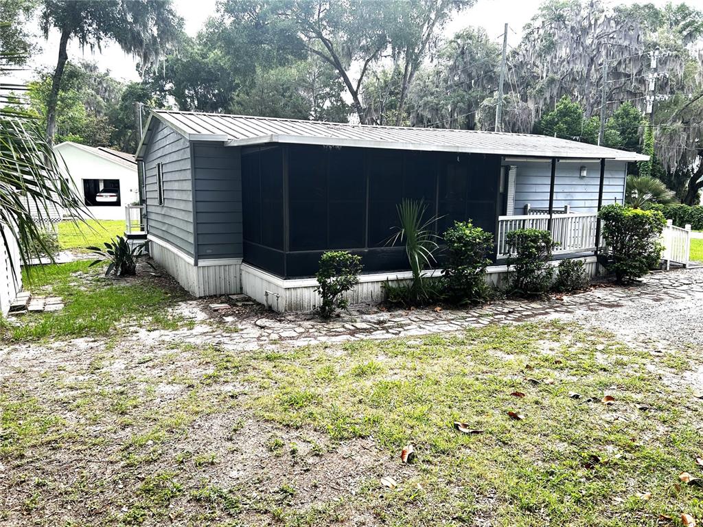 A single-story mobile home features a metal roof, gray siding, and a screened-in front porch — 3935 E LAKE PARK DRIVE, HERNANDO, FL