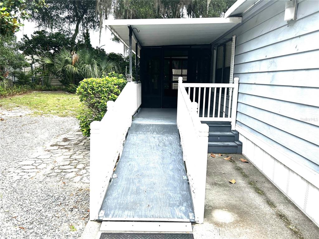 A wooden wheelchair ramp leads to the screened porch entrance of a mobile home — 3935 E LAKE PARK DRIVE, HERNANDO, FL