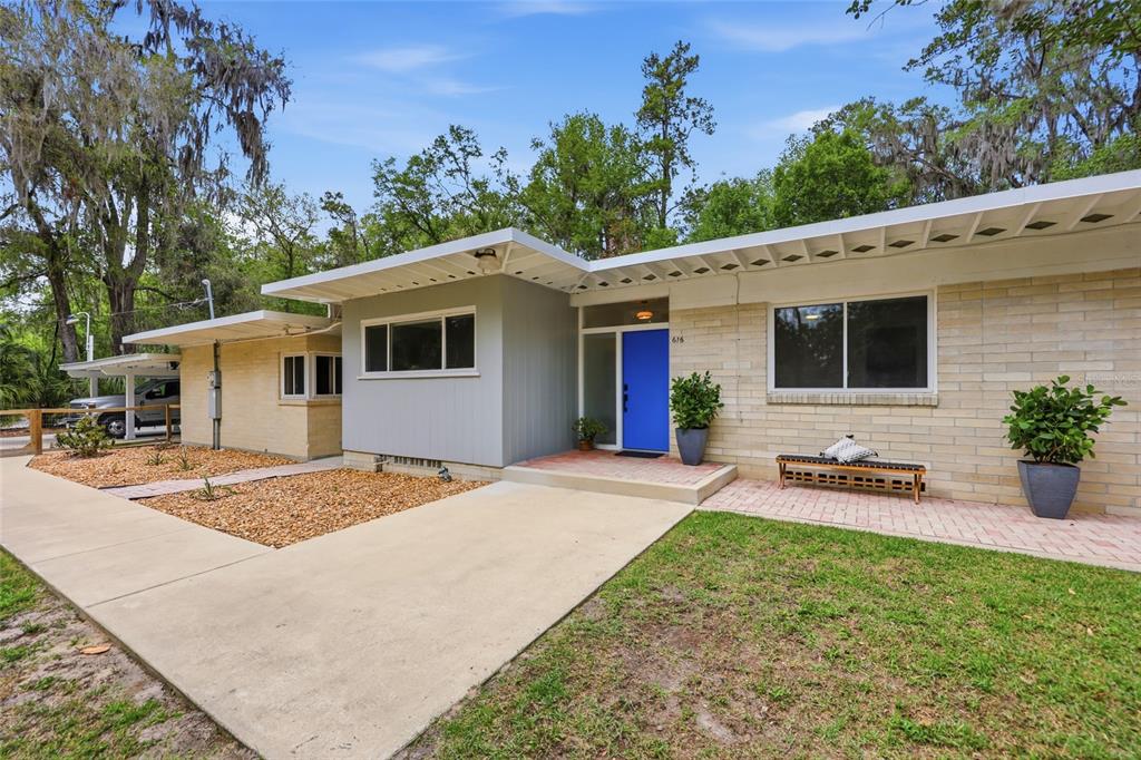 A single-story house with a blue front door, brick siding, and a concrete driveway — 616 SW 21ST AVENUE, GAINESVILLE, FL