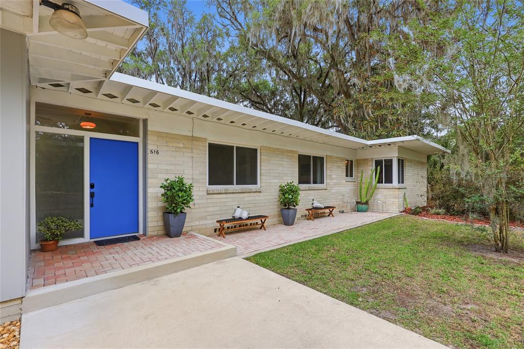 A single-story brick house features a bright blue front door and a brick patio — 616 SW 21ST AVENUE, GAINESVILLE, FL