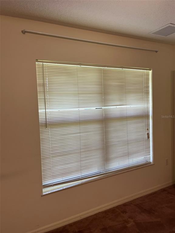 A room with beige walls, brown carpet, and a window covered by horizontal blinds — 8451 SW 14TH LANE, OKEECHOBEE, FL