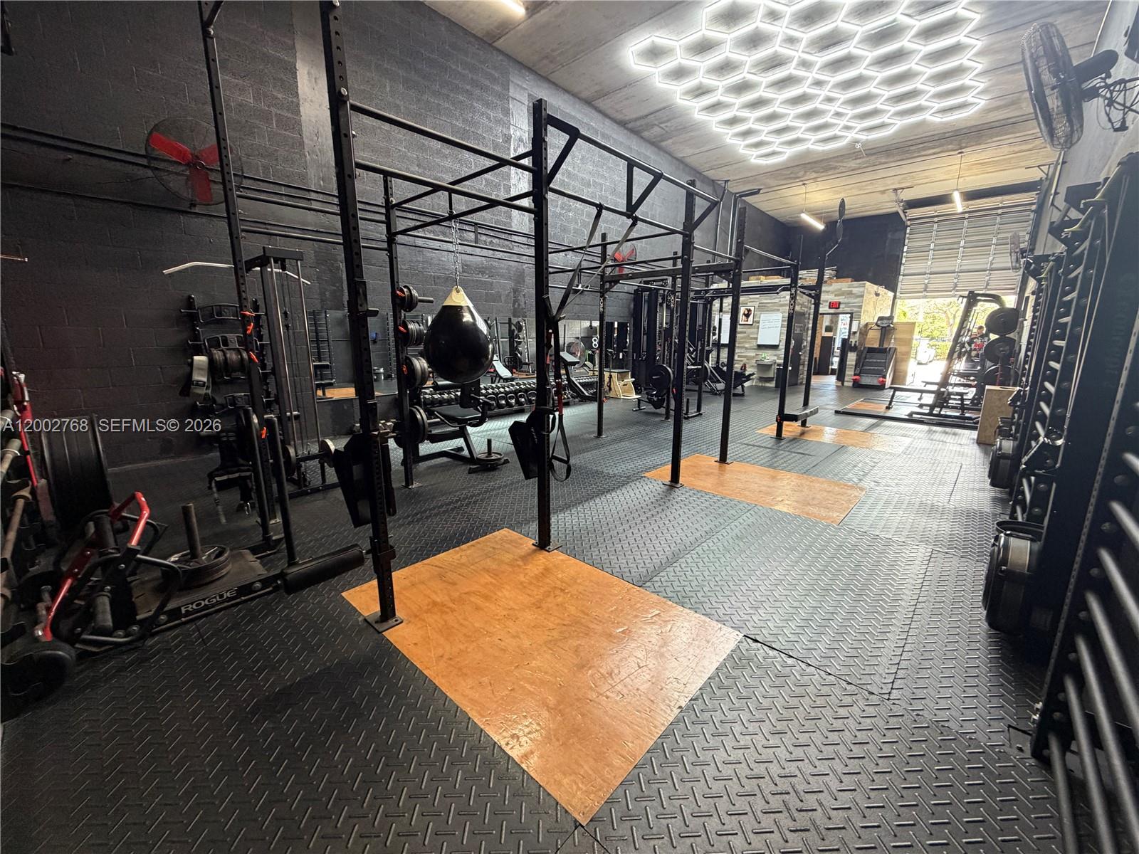 A gym interior features a large metal rig, rubber flooring, and hexagonal ceiling lights — 14911 SW 137th St, Kendall FL 33196, KENDALL, FL