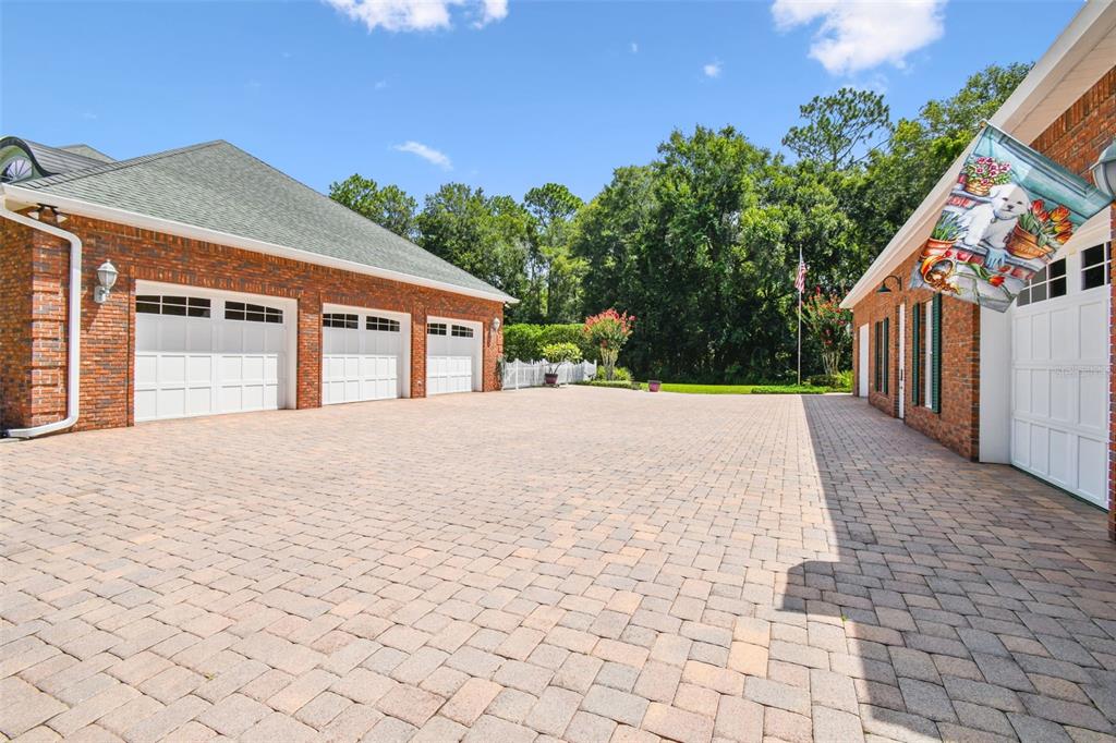 A brick house with a three-car garage and a large paved driveway under a blue sky — 1745 TAYLOR WOODS ROAD, DELAND, FL