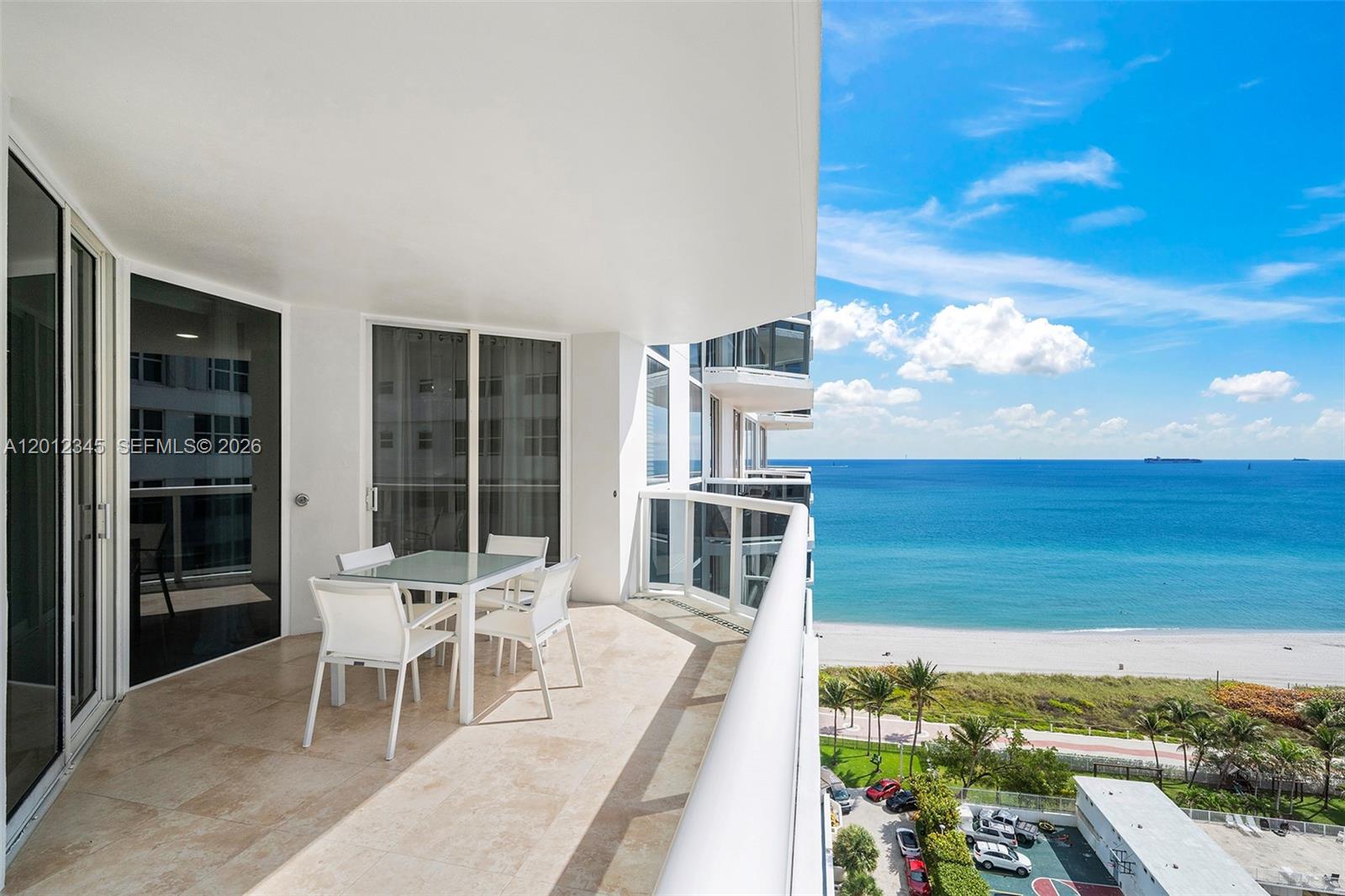 A balcony with a dining set overlooks the ocean and a beach — 4775 Collins Ave # 1504, Miami Beach FL 33140, MIAMI BEACH, FL