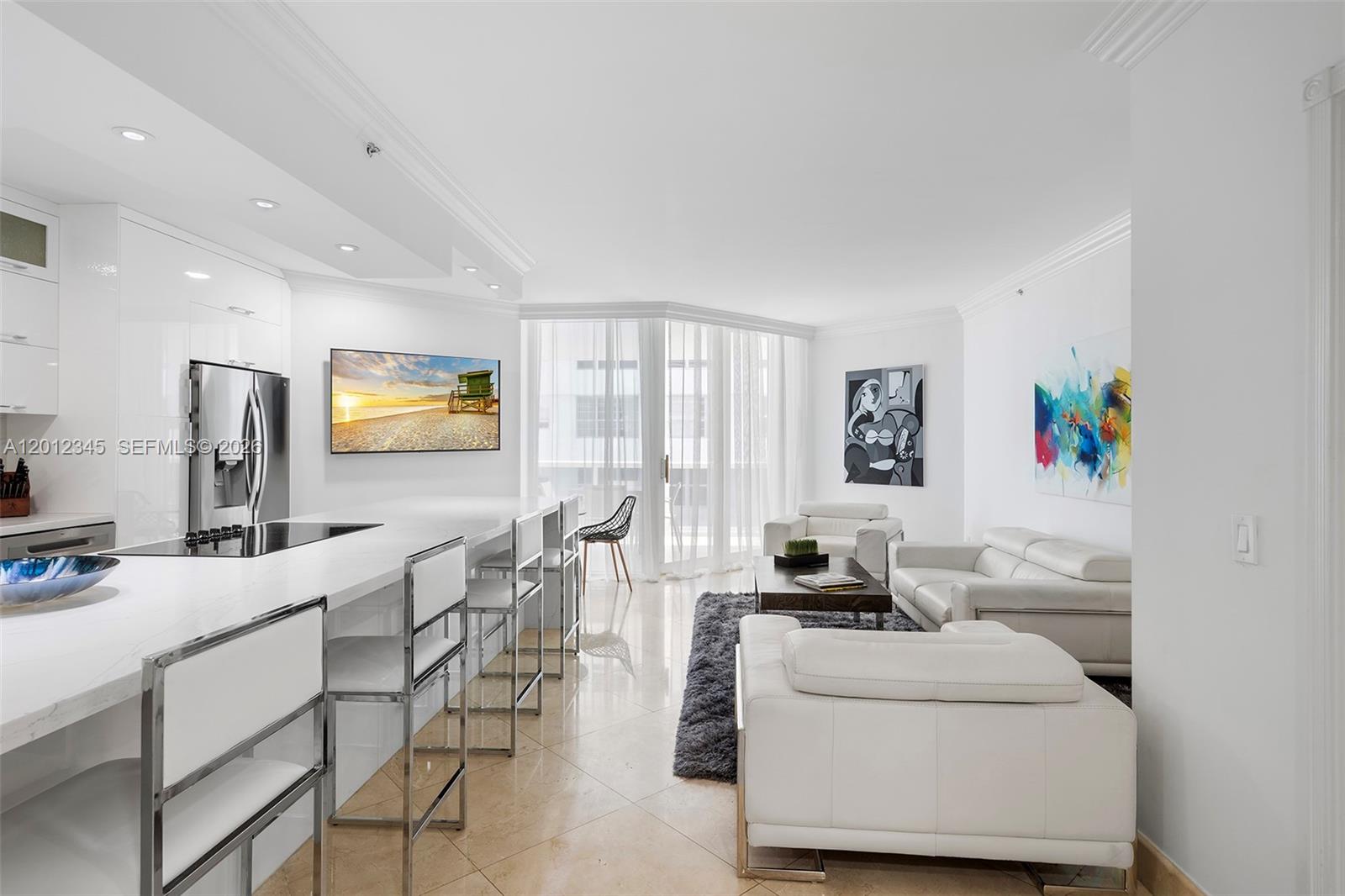 A modern open-concept living room and kitchen featuring white cabinetry, leather furniture, and tile floors — 4775 Collins Ave # 1504, Miami Beach FL 33140, MIAMI BEACH, FL