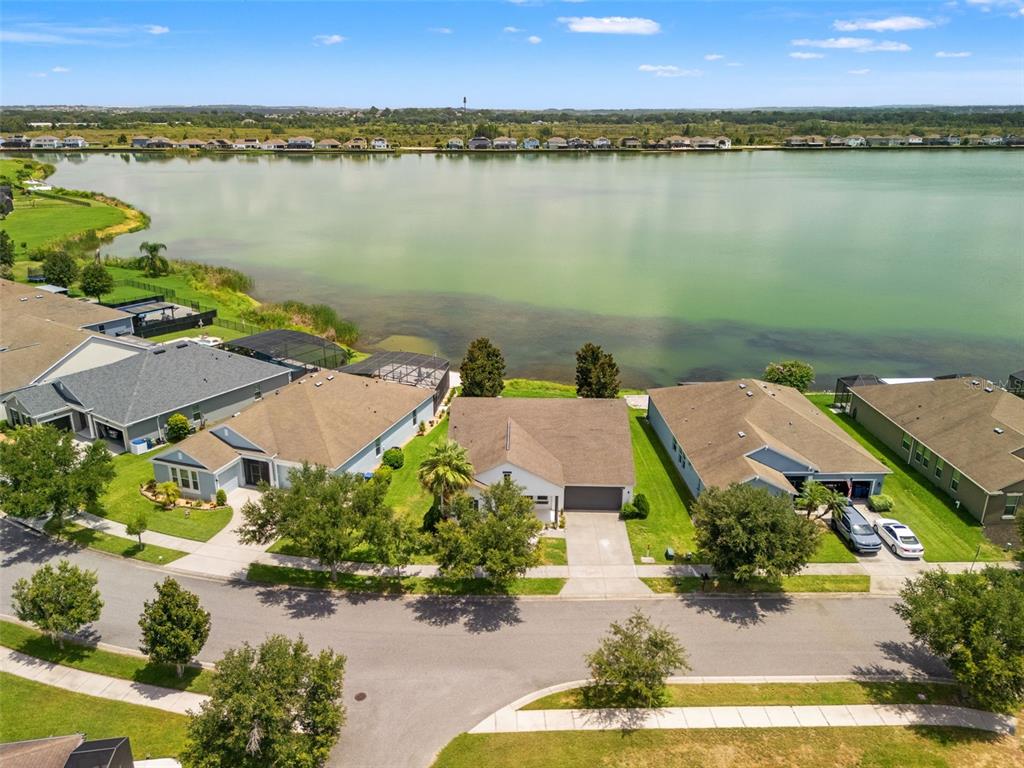 An aerial view shows suburban houses with backyards facing a large lake — 259 BLUE CYPRESS DRIVE, GROVELAND, FL