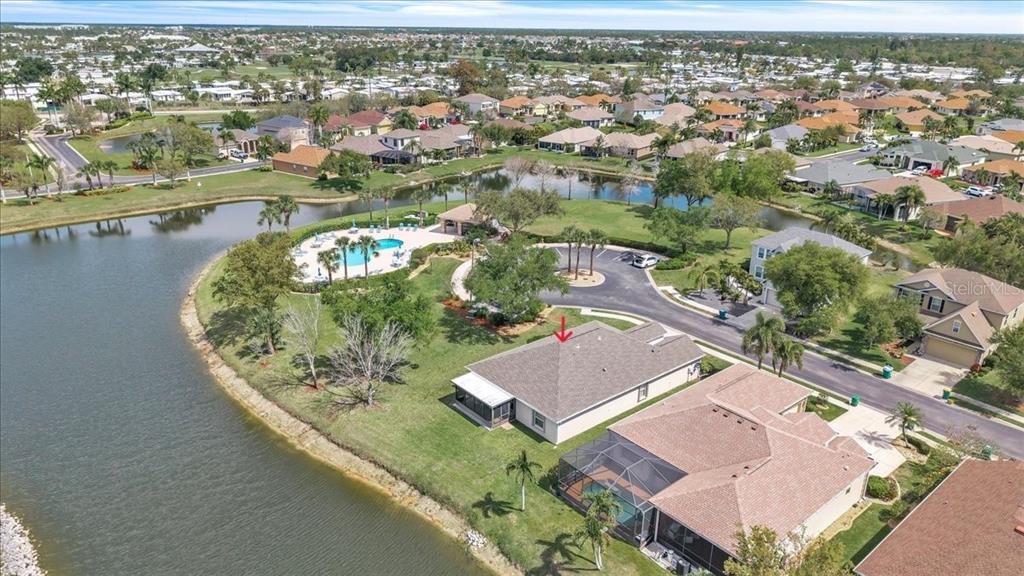 An aerial view of a suburban house with a pool cage next to a lake — 24483 LAKESIDE MANOR, PORT CHARLOTTE, FL