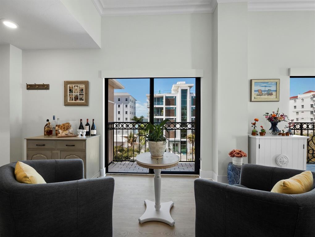 A living area features two gray armchairs, a small round table, and a balcony view — 205 GOLDEN GATE POINT UNIT 401, SARASOTA, FL