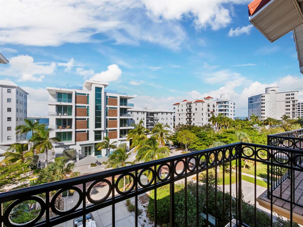 A view from a balcony overlooking palm trees and several multi-story apartment buildings — 205 GOLDEN GATE POINT UNIT 401, SARASOTA, FL