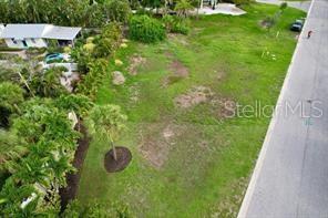 An aerial view shows a vacant, grassy residential lot bordered by a road and trees — 521 NEPTUNE AVENUE, LONGBOAT KEY, FL