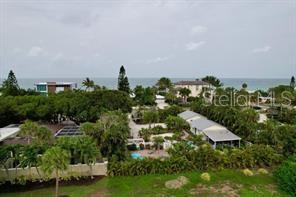 An aerial view shows coastal homes surrounded by lush trees near the ocean — 521 NEPTUNE AVENUE, LONGBOAT KEY, FL