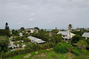 An elevated view of a coastal neighborhood with houses, lush trees, and the ocean beyond — 521 NEPTUNE AVENUE, LONGBOAT KEY, FL