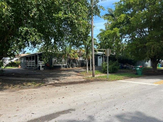 A single-story house with dark gray siding and a tiled roof sits behind a driveway — 335 NE 114th St, Miami FL 33161, MIAMI, FL