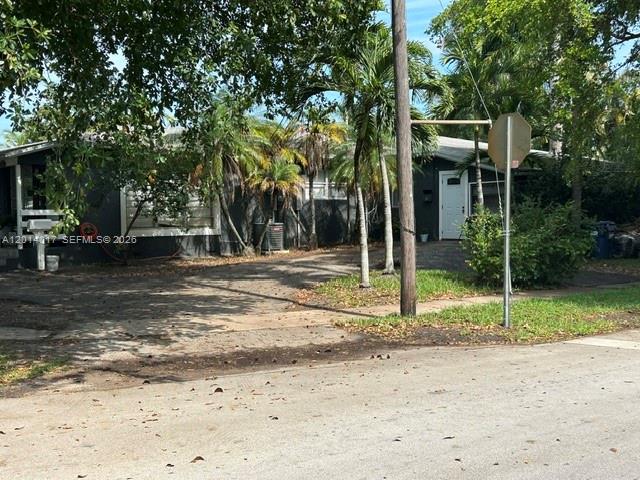 A paved road leads toward a house partially obscured by large, leafy trees — 335 NE 114th St, Miami FL 33161, MIAMI, FL