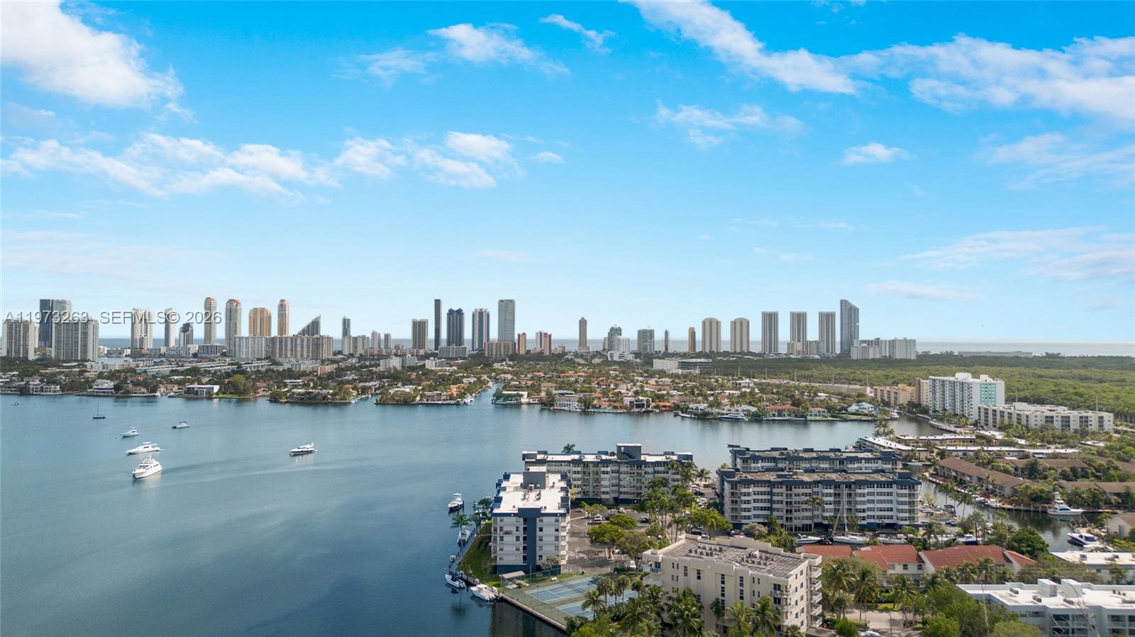 An aerial view shows a waterfront residential area with high-rise buildings and a distant skyline — 16385 Biscayne Blvd # 1502, North Miami Beach FL 33160, NORTH MIAMI BEACH, FL