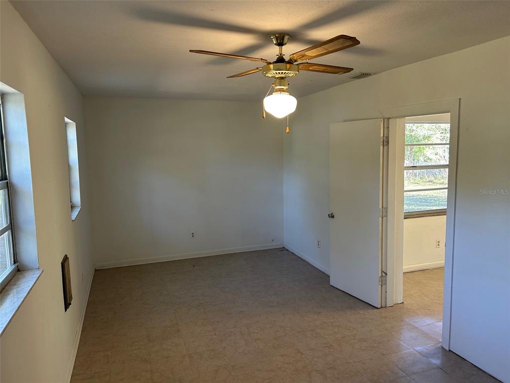 An empty room features a ceiling fan, white walls, tile flooring, and a doorway — 7001 32ND AVENUE S, TAMPA, FL
