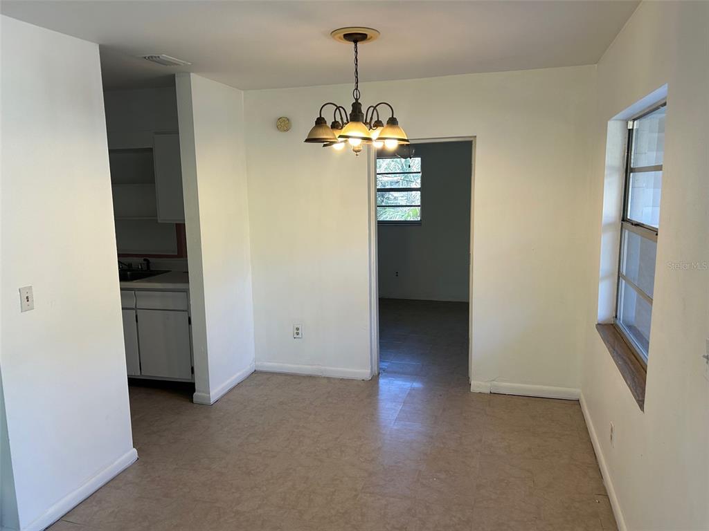 A dining area features a chandelier, tile flooring, and an open doorway to another room — 7001 32ND AVENUE S, TAMPA, FL