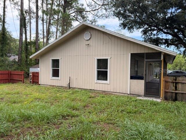 The exterior of a single-story house features light-colored vertical siding and a screened-in porch — 1427 ANNAPOLIS AVENUE, DAYTONA BEACH, FL