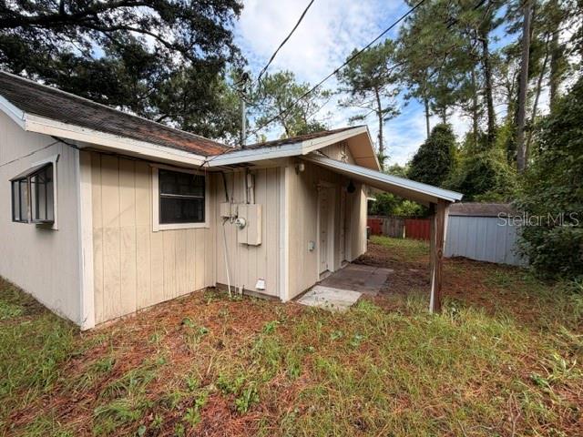 The exterior of a light-colored wood-sided house features a small covered porch and a window — 1427 ANNAPOLIS AVENUE, DAYTONA BEACH, FL