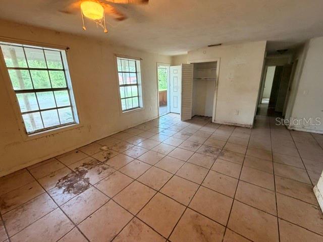An empty room with beige tile flooring, two windows, and a ceiling fan — 1427 ANNAPOLIS AVENUE, DAYTONA BEACH, FL