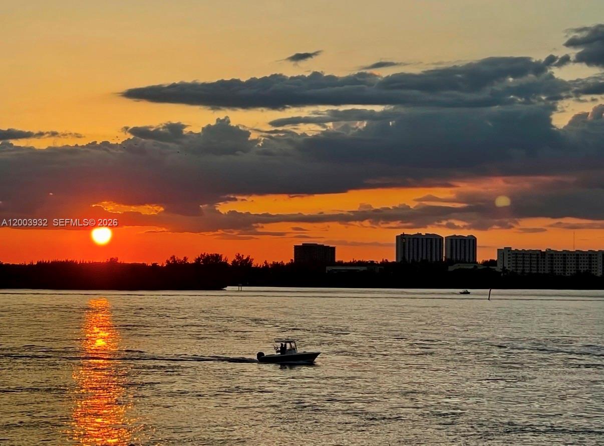 A small boat travels across a body of water during a vibrant sunset — 286 Bal Bay Dr # 2B, Bal Harbour FL 33154, BAL HARBOUR, FL