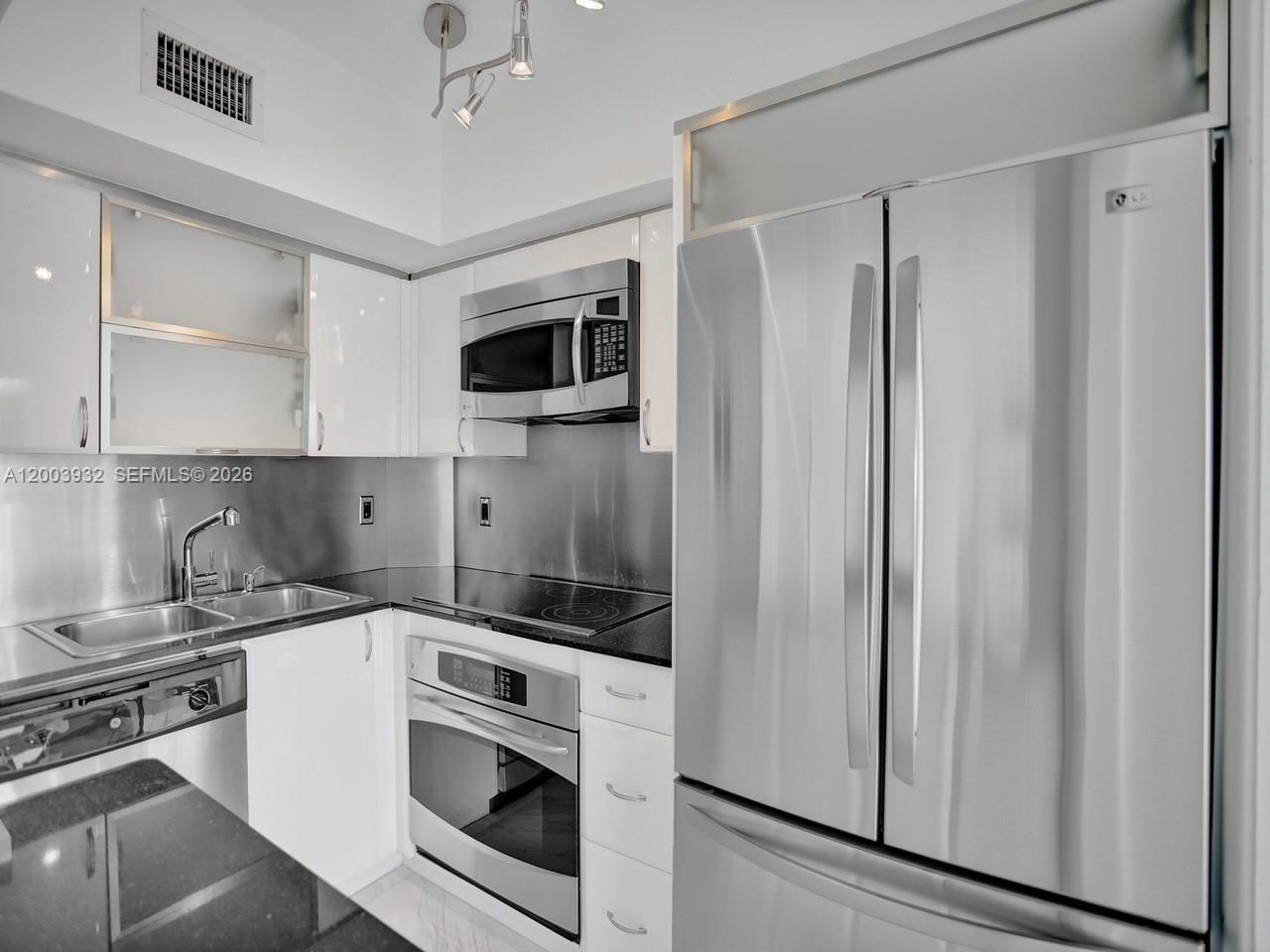 A modern kitchen features white cabinets, stainless steel appliances, and a black countertop — 286 Bal Bay Dr # 2B, Bal Harbour FL 33154, BAL HARBOUR, FL