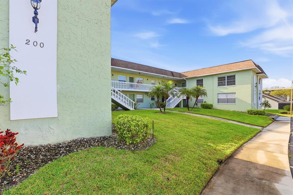 A two-story apartment building with light green stucco walls and an exterior staircase — 1250 S PINELLAS AVENUE UNIT 214, TARPON SPRINGS, FL