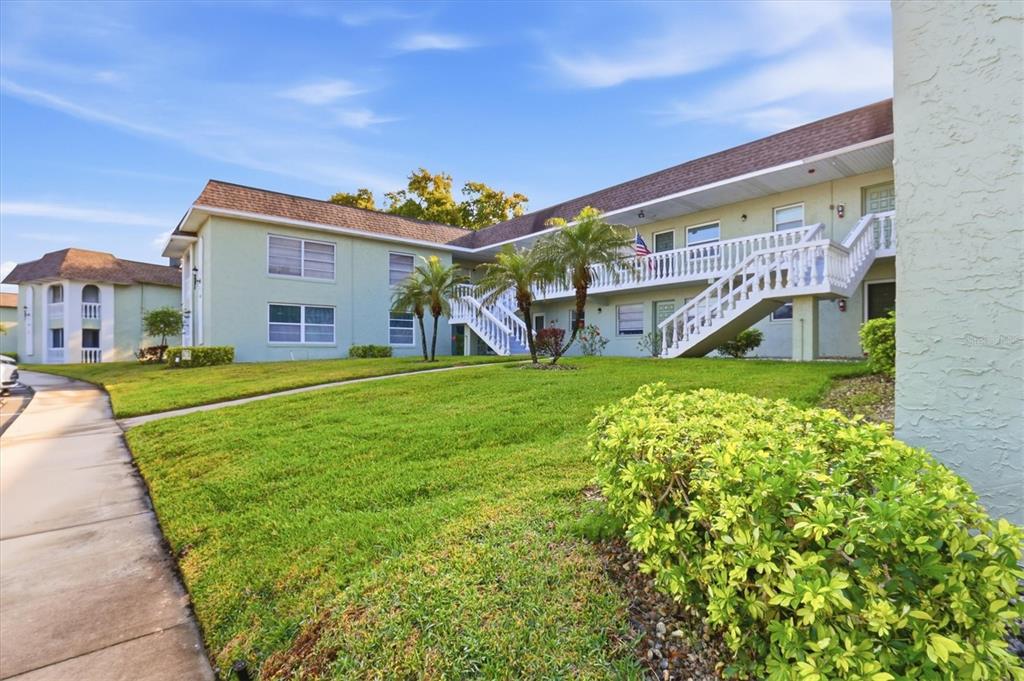 A two-story apartment building with a white exterior staircase and green lawn — 1250 S PINELLAS AVENUE UNIT 214, TARPON SPRINGS, FL