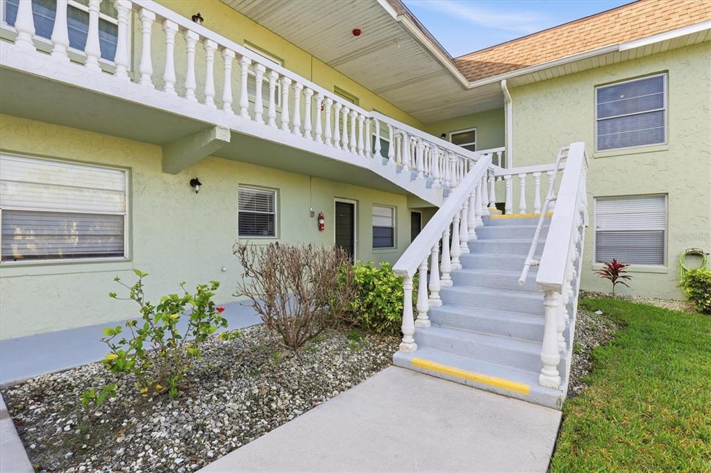 A two-story apartment building exterior features a concrete staircase leading to an upper balcony — 1250 S PINELLAS AVENUE UNIT 214, TARPON SPRINGS, FL