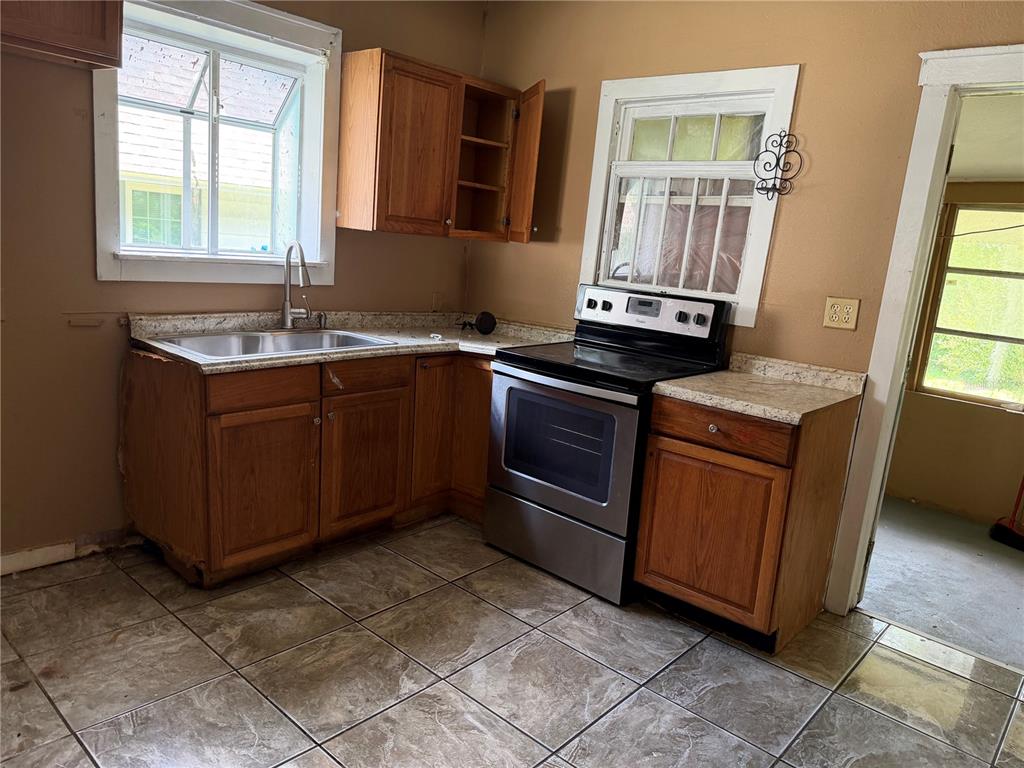 A kitchen features wooden cabinets, a stainless steel stove, a sink, and tiled flooring — 444 AVENUE B NE, WINTER HAVEN, FL