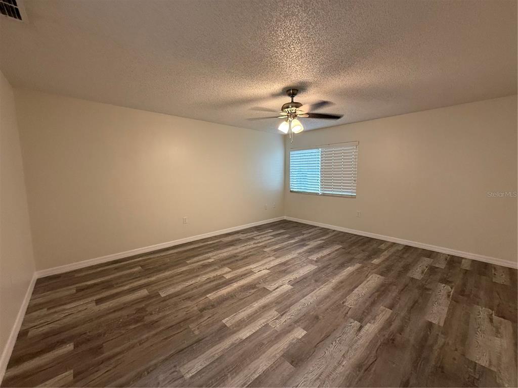 An empty bedroom features light-colored walls, a ceiling fan, and wood-look laminate flooring — 702 COUNTRY LANE NE UNIT 702, WINTER HAVEN, FL